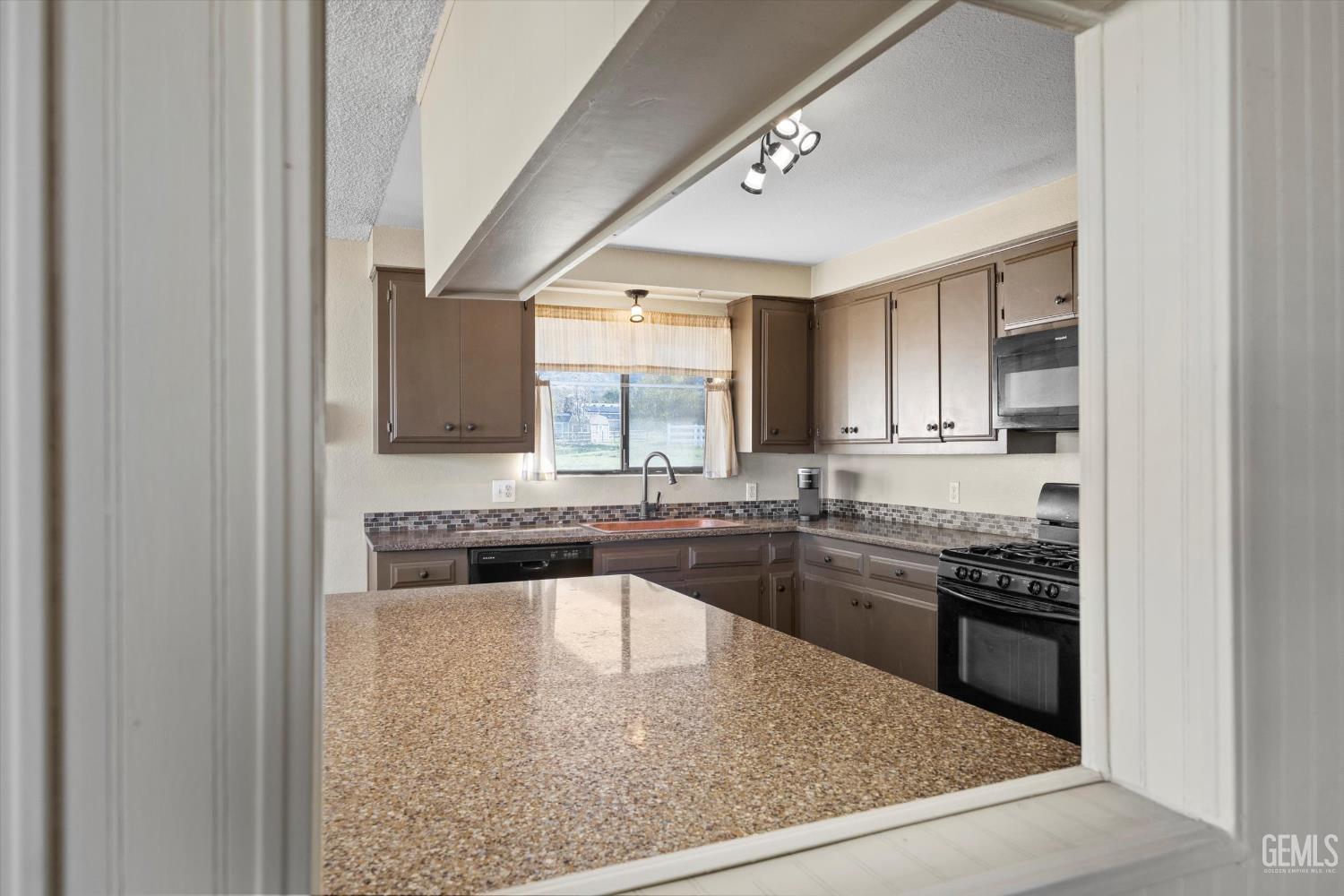 Undisclosed Address Tehachapi, CA 93561 - Photo 17 of 40 a kitchen with kitchen island granite countertop a stove a sink and a refrigerator