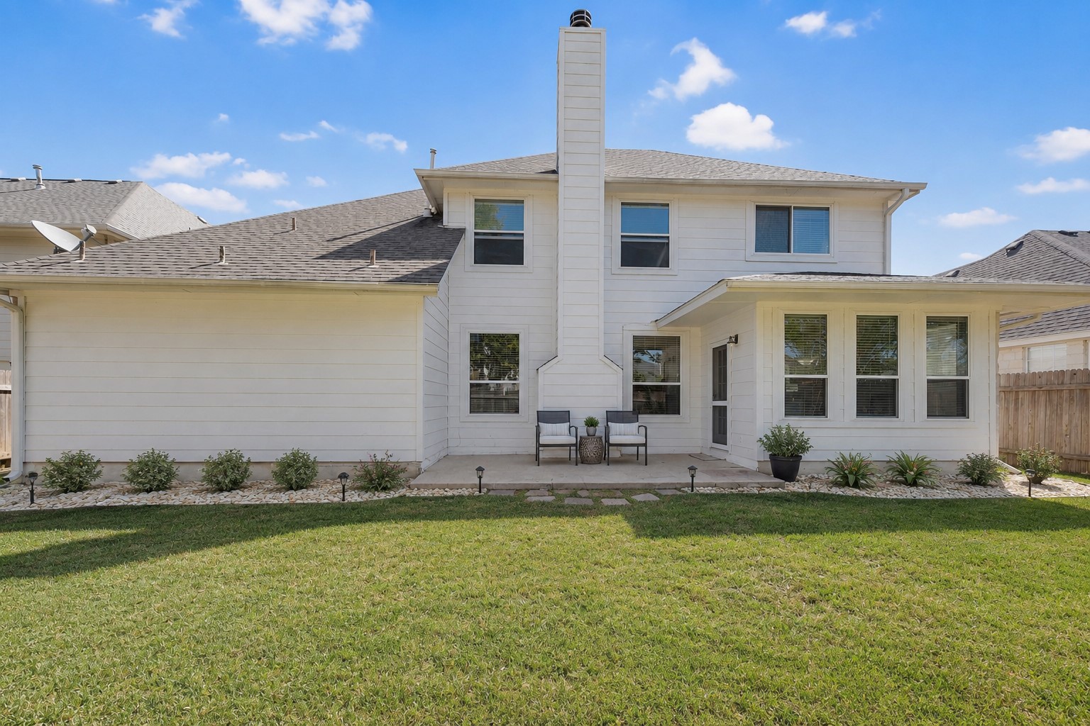 12528 Labrador Cove Austin, TX 78729 - Photo 36 of 40 Step outside and enjoy a spacious backyard retreat designed for both relaxation and entertaining. The covered patio offers the perfect spot for morning coffee or evening gatherings, while the expansive lawn provides plenty of room for play, pets, gardening, or future outdoor enhancements. The photo has been virtually enhanced to illustrate a possible outdoor lifestyle setting, showcasing the potential for comfortable seating and attractive landscaping. With attractive white exterior siding, mature neighborhood surroundings, and a fully fenced yard, this outdoor space combines privacy, functionality, and low-maintenance living in a setting you’ll enjoy year-round.