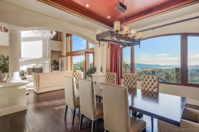 a view of a dining room with furniture large windows a chandelier and wooden floor