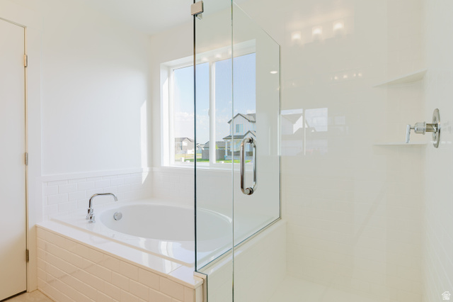 433 North 600 West Smithfield, UT 84335 - Photo 33 of 40 Soaking tub with a polished chrome faucet, glass-enclosed shower, white subway tile surround, built-in shower shelving, and overhead recessed lighting