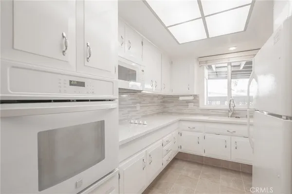 a kitchen with white cabinets and white appliances