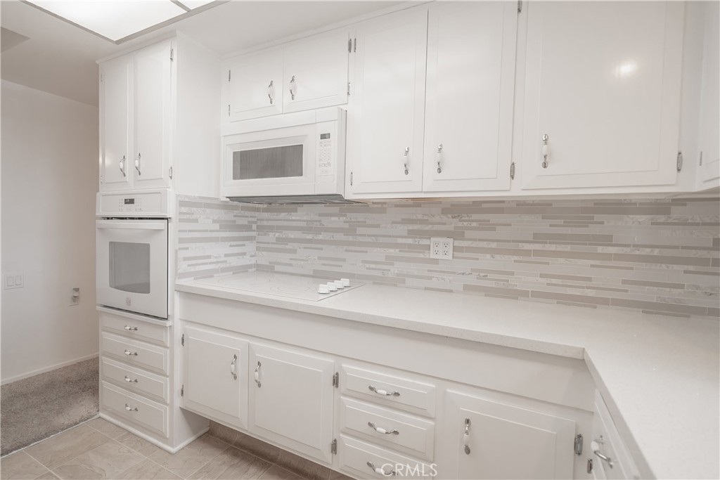 1880 St John Road Seal Beach, CA 90740 - Photo 9 of 30 a kitchen with white cabinets and white appliances