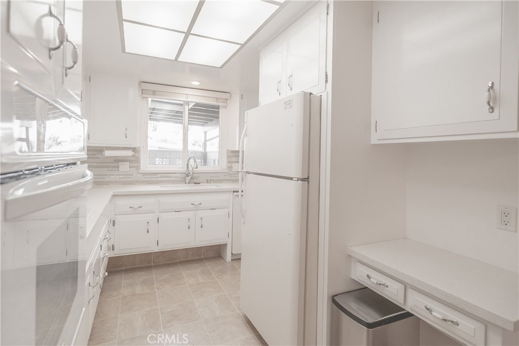 1880 St John Road Seal Beach, CA 90740 - Photo 10 of 30 a kitchen with white cabinets and white appliances