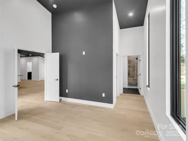 an empty room that has two windows and wooden door