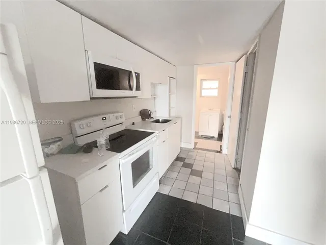 a view of a kitchen with a sink and a washer dryer