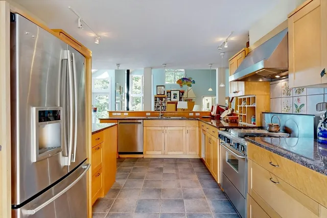 a kitchen with stainless steel appliances granite countertop a refrigerator a stove and a sink