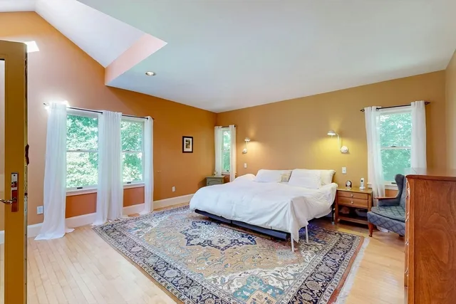 a bed sitting in a spacious bedroom next to a window