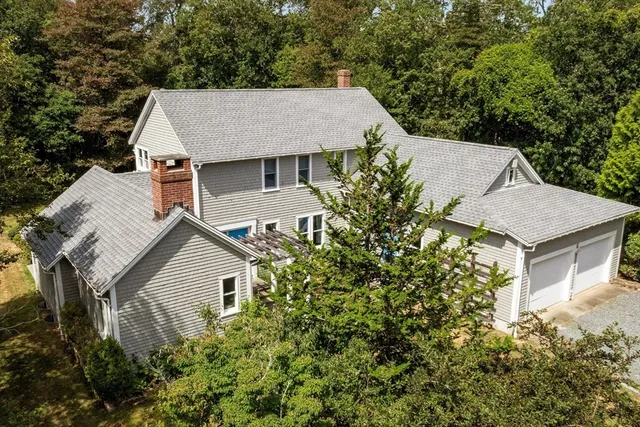 an aerial view of a house with yard and trees in the background