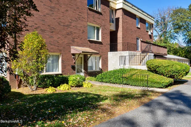 a view of a brick house with a yard and plants
