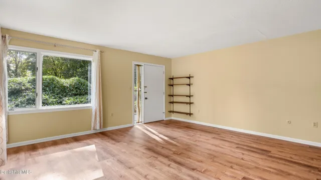 a view of an empty room with a window and wooden floor