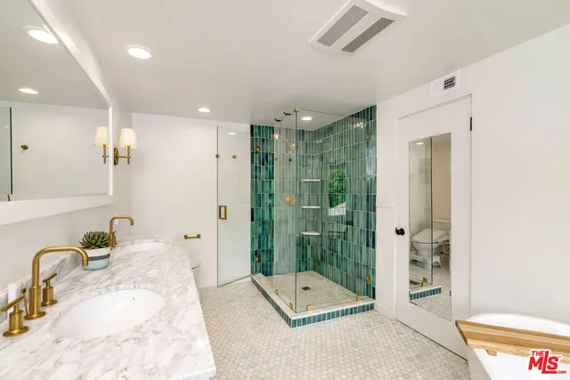 a bathroom with a tub shower sink and mirror