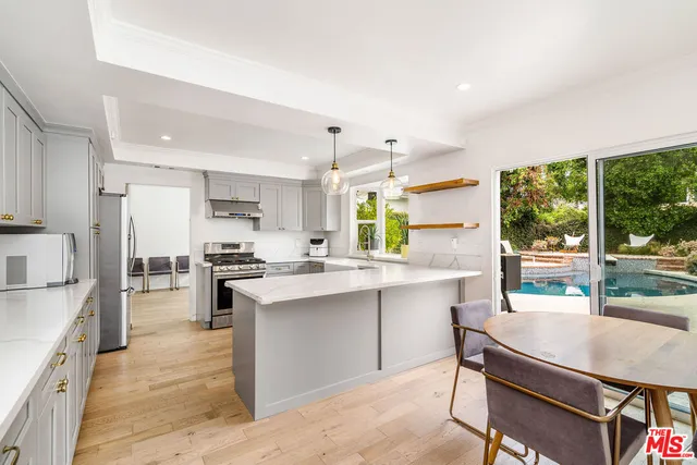 a kitchen with stainless steel appliances a table chairs refrigerator and sink