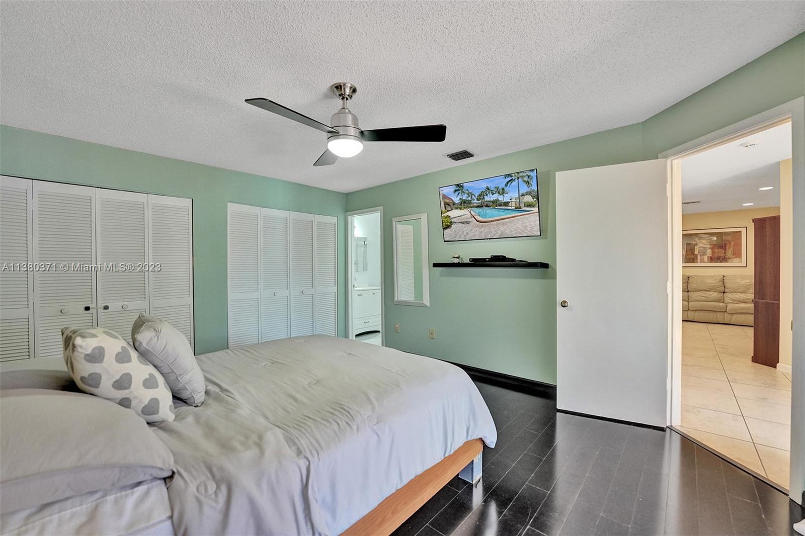 23360 Southwest 53rd Avenue, Unit E Boca Raton, FL 33433 - Photo 18 of 37 a bedroom with a large bed and a chandelier