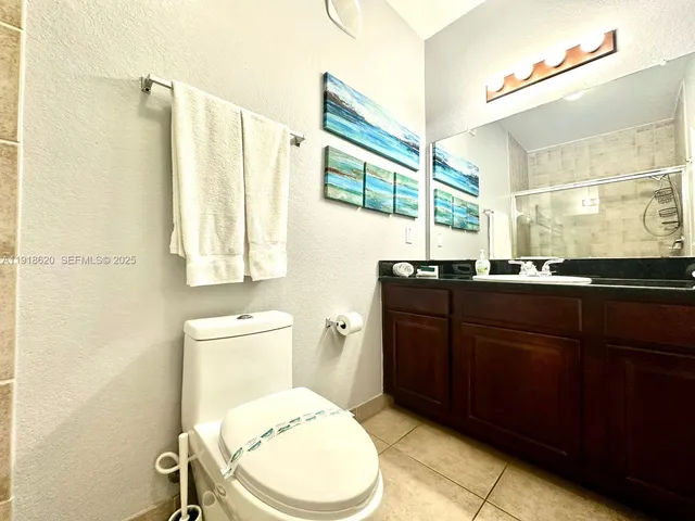 a bathroom with a granite countertop toilet sink and mirror