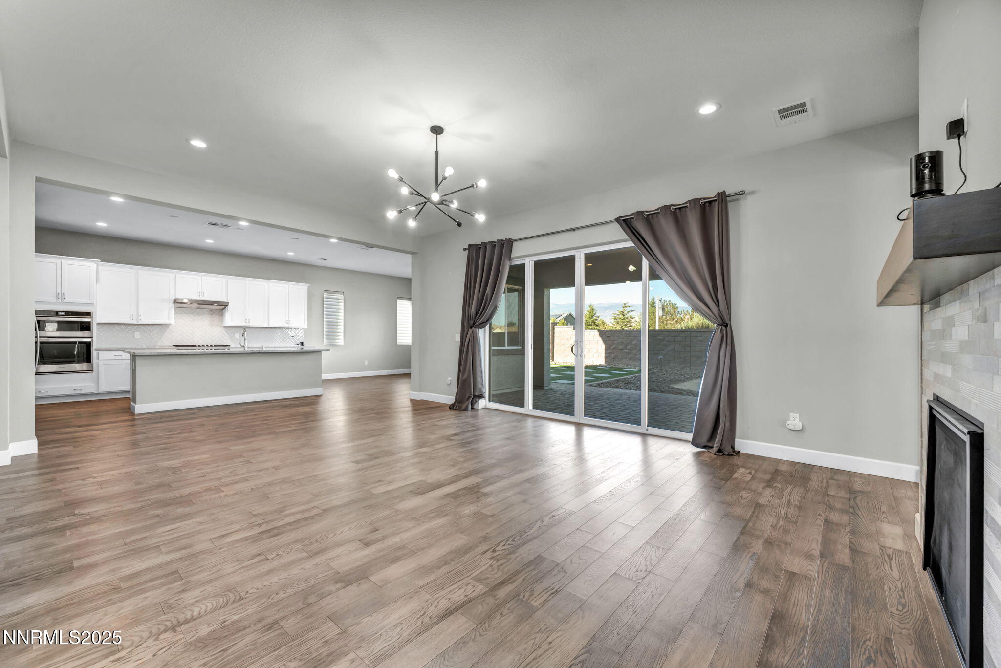 9267 Blue Basin Trail Reno, NV 89521 - Photo 23 of 68 a view of an empty room with wooden floor and a kitchen