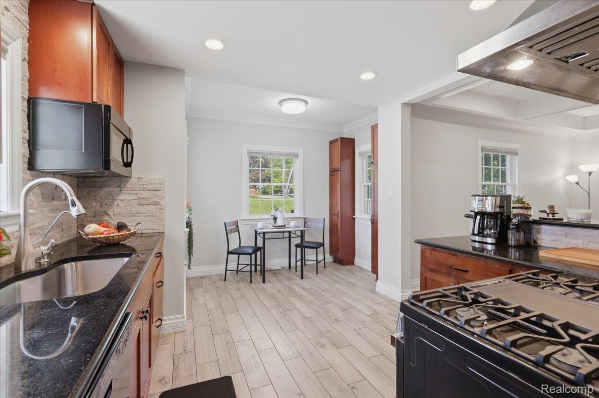 5685 Crescent Road Waterford, MI 48327 - Photo 13 of 47 Open-concept kitchen featuring wood-finish cabinetry, dark countertops, and light wood-look flooring
