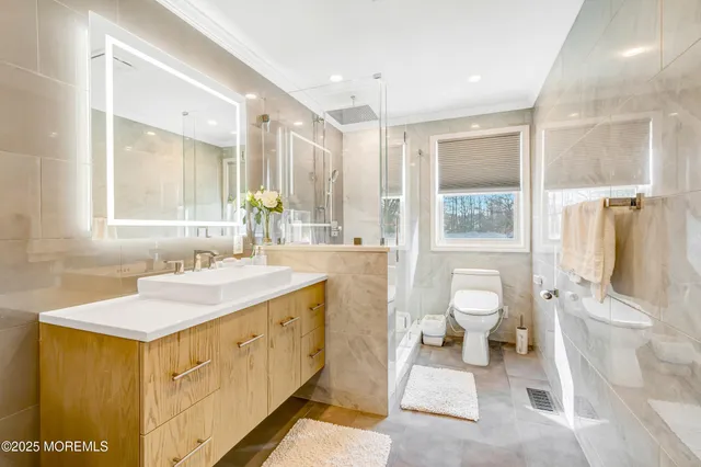 a spacious bathroom with a sink a toilet and a large mirror