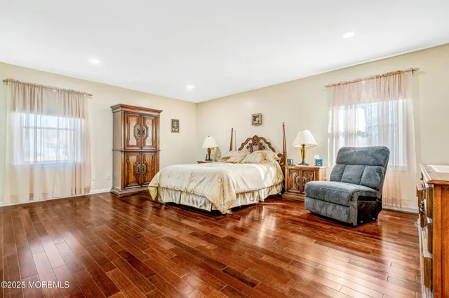 a spacious bedroom with a bed a couch and a large window with wooden floor