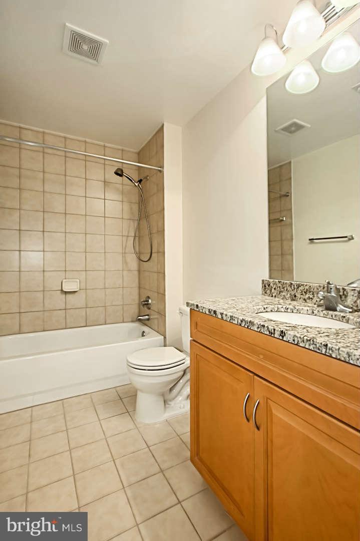 1111 25th Street Northwest, Unit 714 Washington, DC 20037 - Photo 22 of 28 a bathroom with a granite countertop toilet a sink and a bathtub