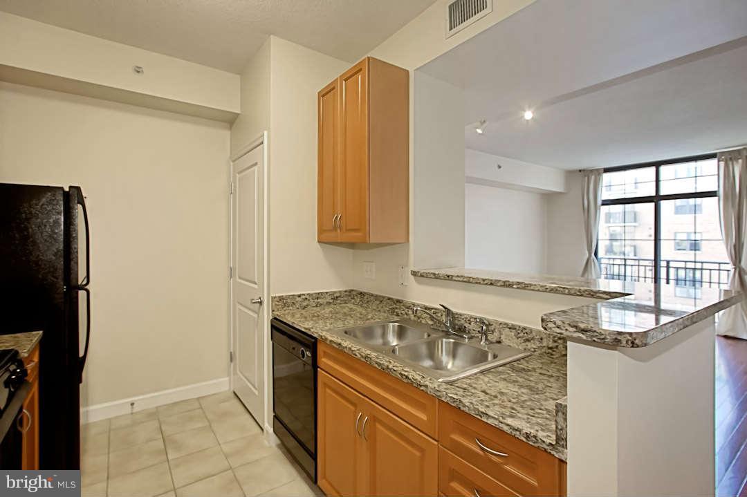 1111 25th Street Northwest, Unit 714 Washington, DC 20037 - Photo 9 of 28 a kitchen with granite countertop a sink and a refrigerator