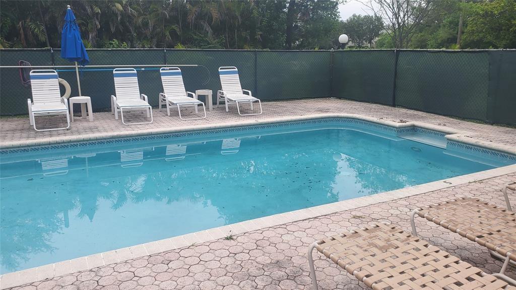 3910 Crystal Lake Drive, Unit 403 Deerfield Beach, FL 33064 - Photo 5 of 27 a backyard of a house with table and chairs