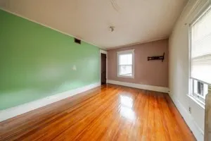 a view of empty room with window and wooden floor