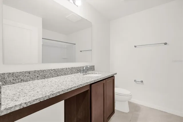 a bathroom with a granite countertop sink a toilet and a mirror