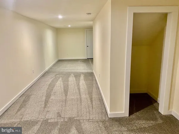 a view of a hallway with wooden floor and a bathroom