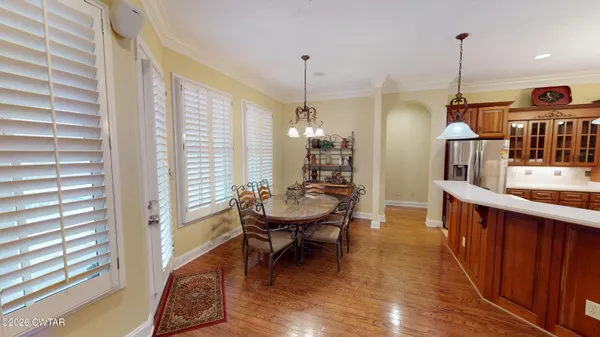 a kitchen with a refrigerator a sink dishwasher and a dining table with wooden floor