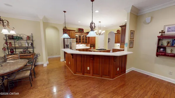 a kitchen that has a sink a microwave oven a stove and a dining table with wooden floor