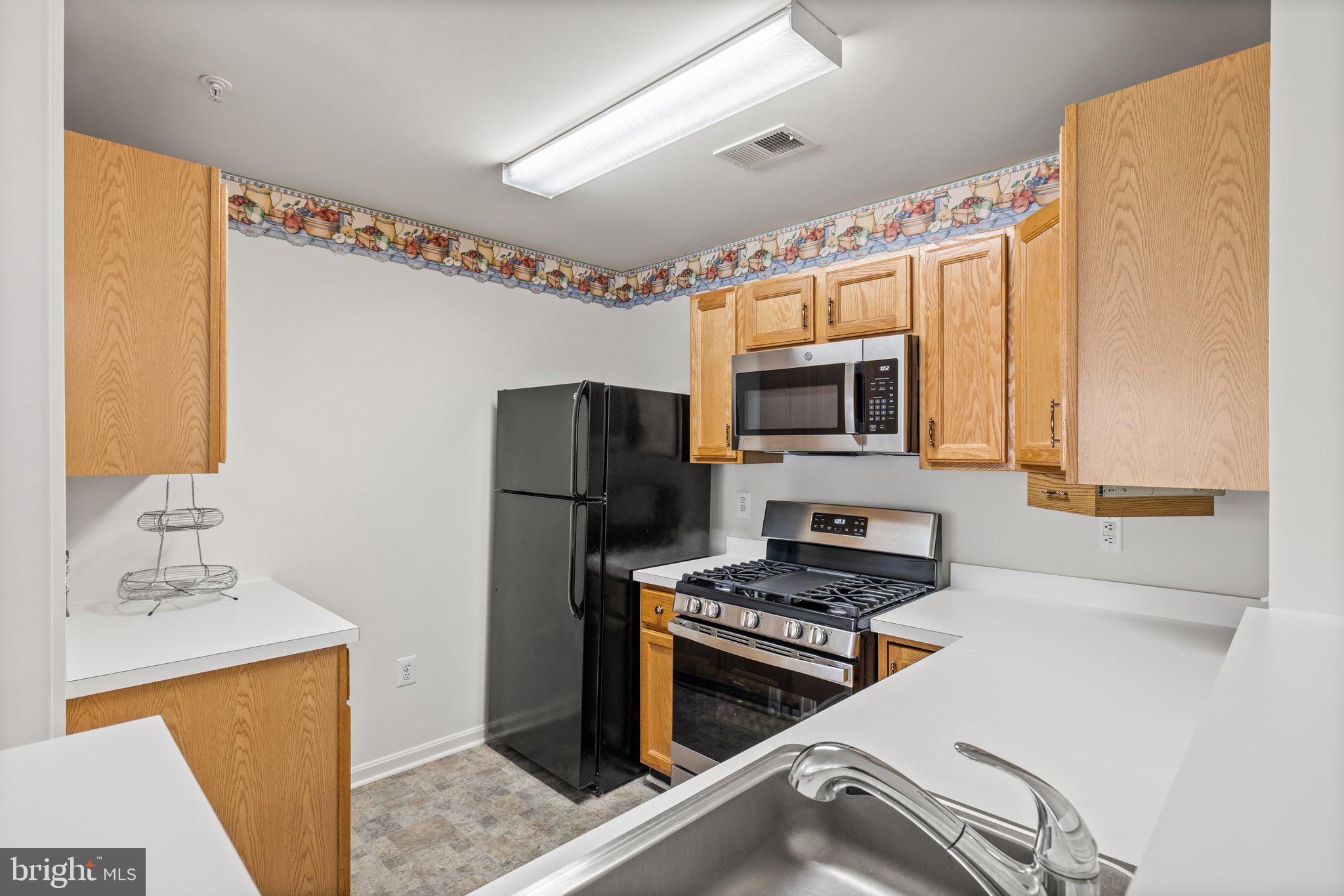 1049 Gardenview Loop, Unit 203 Woodbridge, VA 22191 - Photo 11 of 25 a kitchen with stainless steel appliances a refrigerator and a stove top oven