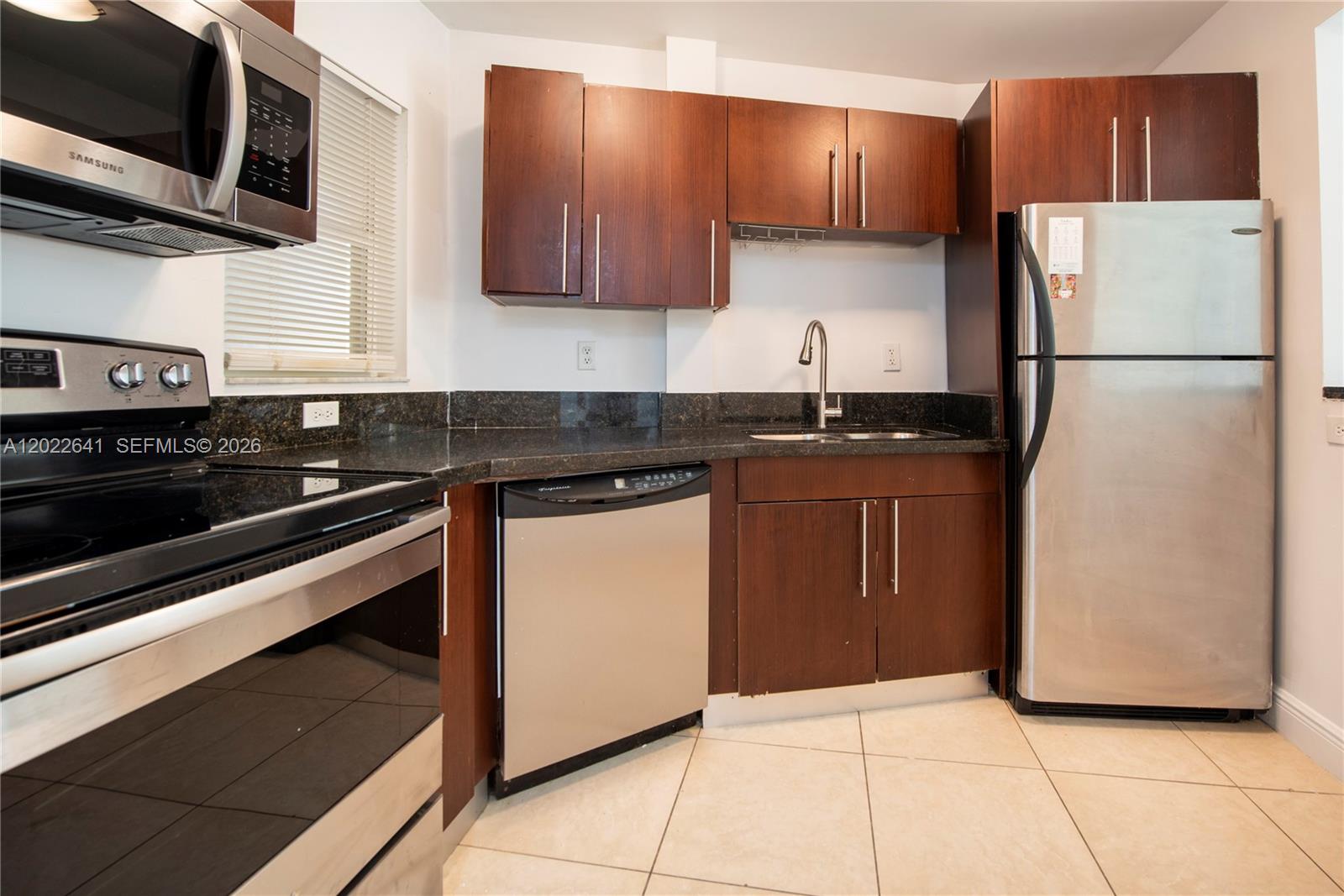 4147 Stirling Road, Unit 105 Dania Beach, FL 33314 - Photo 2 of 16 a kitchen with stainless steel appliances granite countertop a stove a refrigerator and a sink
