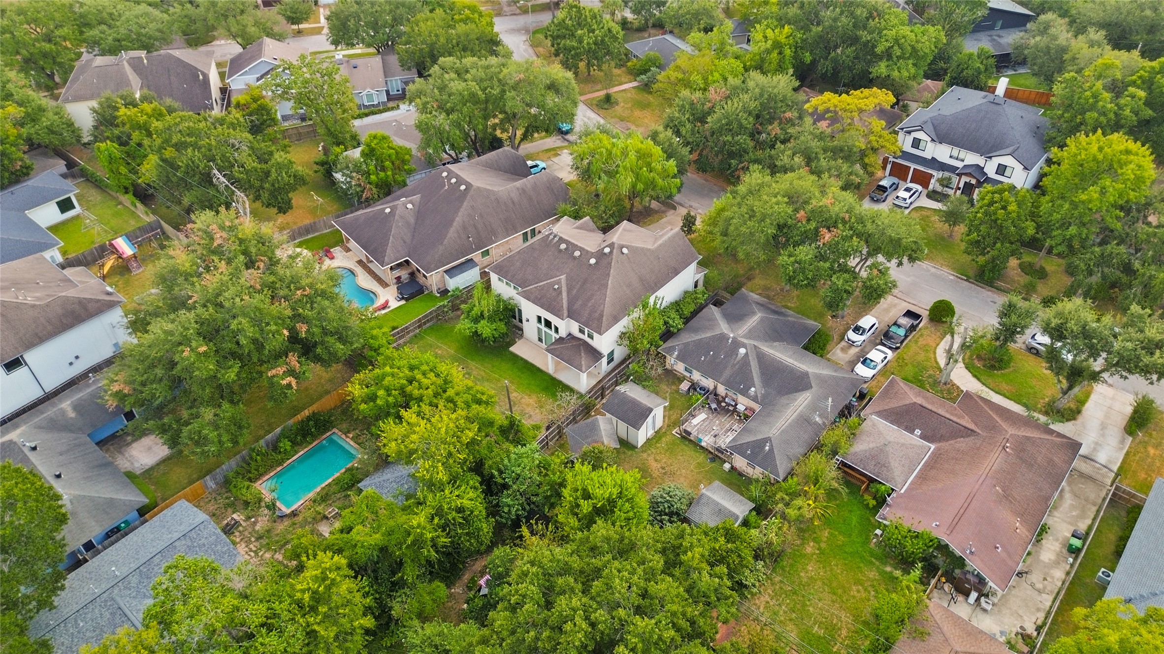 3302 Rochdale Street Houston, TX 77025 - Photo 49 of 50 Take a look at this aerial view of your backyard, showing the covered patio and fenced yard tucked among mature trees for a private, established feel. The surrounding neighborhood is filled with lush greenery, offering a peaceful, tree lined setting from above. It's a great glimpse of how the outdoor space fits within the larger lot and community.