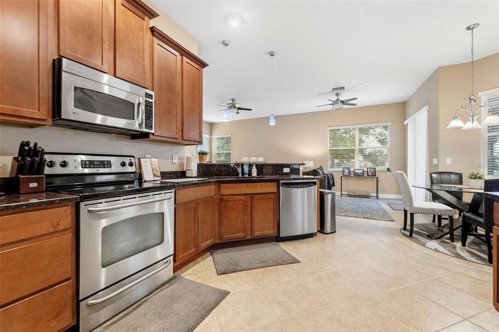 4460 Birchfield Loop Spring Hill, FL 34609 - Photo 11 of 38 a kitchen with stainless steel appliances granite countertop a stove top oven a sink dishwasher a dining table and chairs with wooden floor
