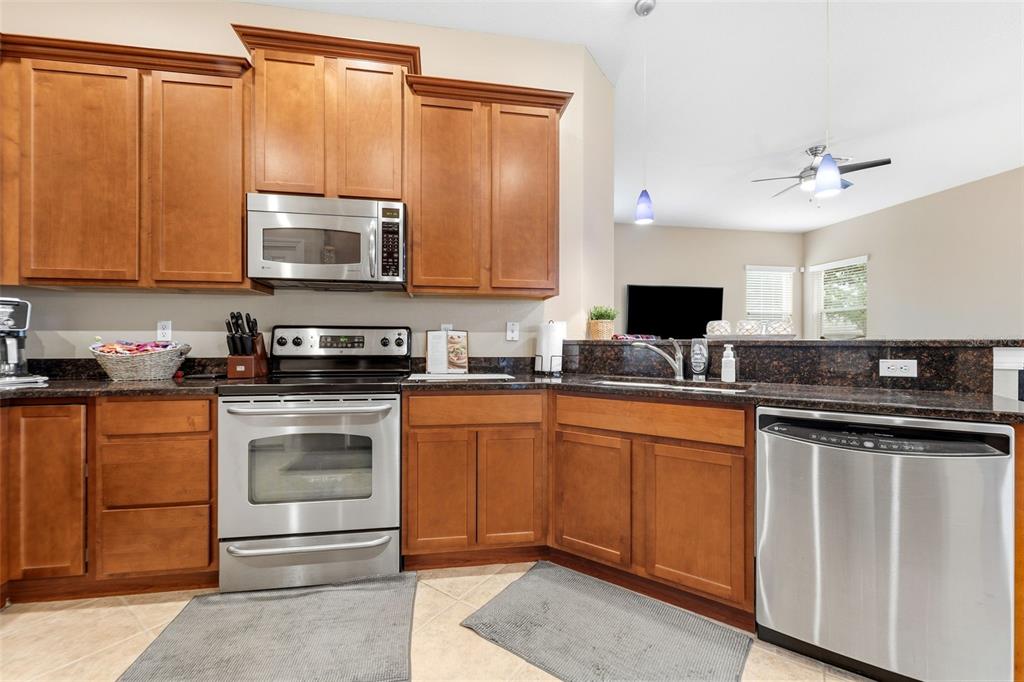 4460 Birchfield Loop Spring Hill, FL 34609 - Photo 12 of 38 a kitchen with stainless steel appliances granite countertop a stove microwave and sink
