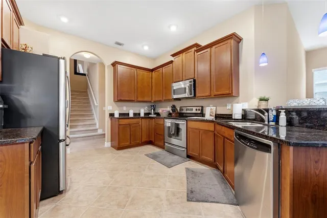 a kitchen with granite countertop a sink a counter top space stainless steel appliances and cabinets