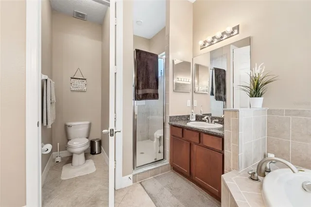 a bathroom with a granite countertop sink a toilet and shower