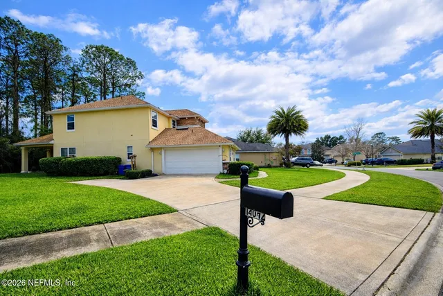 a view of a house with a yard and large tree