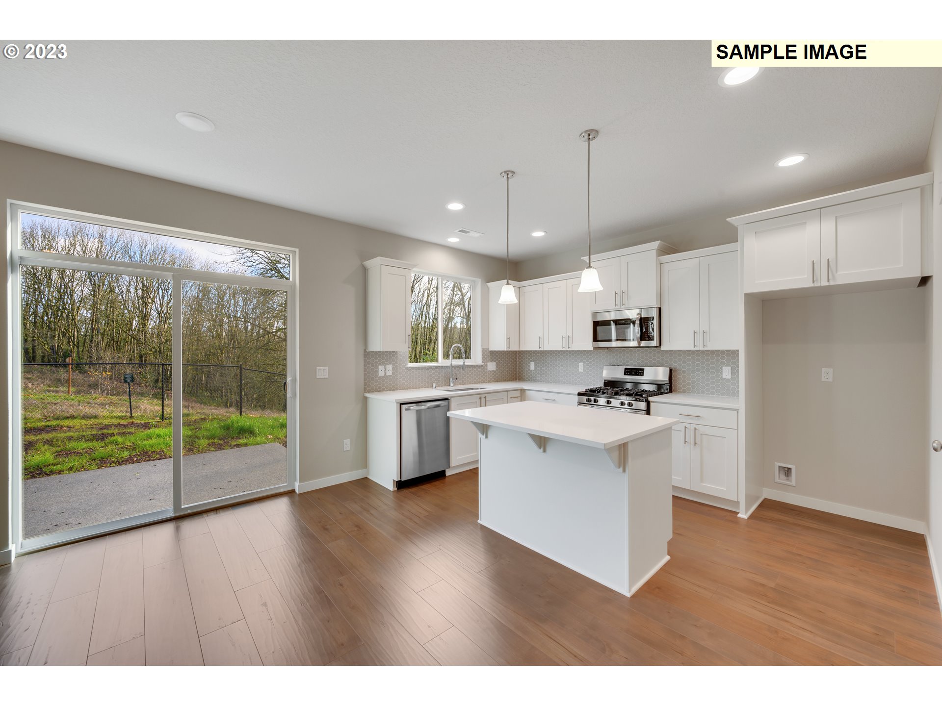 16881 Southeast Mist Layer Loop, Unit 531 Happy Valley, OR 97086 - Photo 7 of 32 a open kitchen with stainless steel appliances granite countertop a refrigerator a sink dishwasher a stove and white countertops with wooden floor