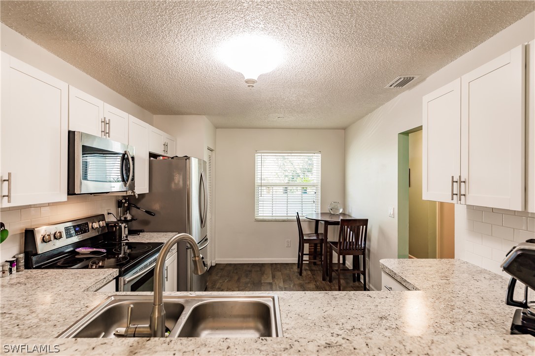 5737 Whitaker Road, Unit C201 Naples, FL 34112 - Photo 11 of 32 a kitchen with a sink stove and refrigerator