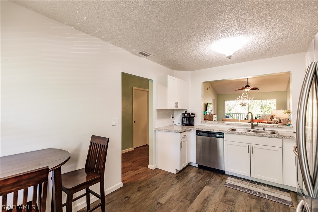 5737 Whitaker Road, Unit C201 Naples, FL 34112 - Photo 12 of 32 a kitchen with a table chairs refrigerator and sink