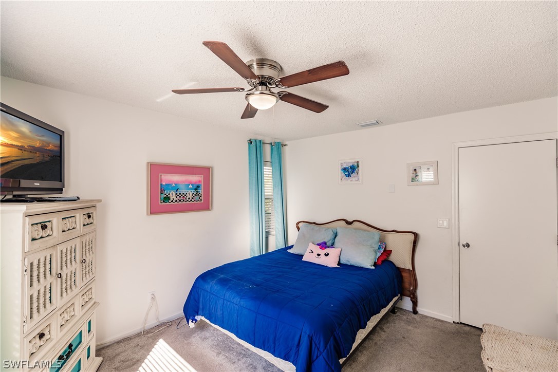 5737 Whitaker Road, Unit C201 Naples, FL 34112 - Photo 19 of 32 a bedroom with a bed and a flat screen tv