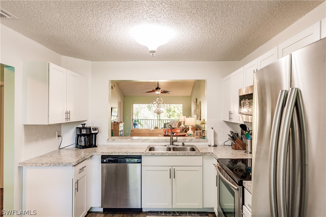 5737 Whitaker Road, Unit C201 Naples, FL 34112 - Photo 10 of 32 a kitchen with stainless steel appliances a sink stove and refrigerator