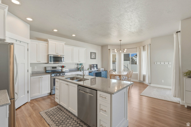 836 South 250 West Vernal, UT 84078 - Photo 22 of 56 Kitchen featuring light wood-type flooring, white cabinetry, stainless steel appliances, and a textured ceiling