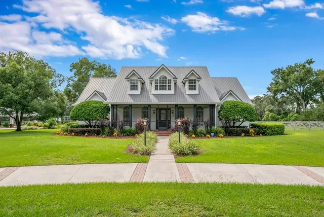 a view of a house with a big yard potted plants and large tree
