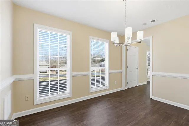 an empty room with wooden floor a ceiling fan and windows