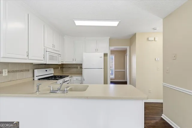 a kitchen with stainless steel appliances granite countertop a refrigerator a sink and white cabinets