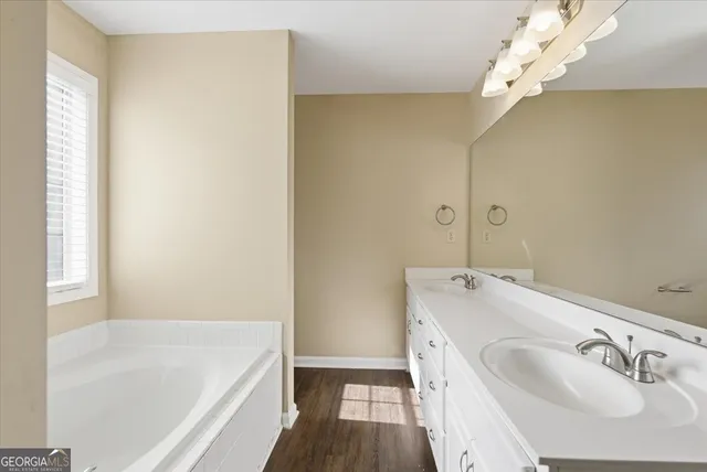 a bathroom with a tub sink and mirror