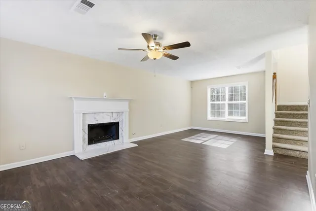 an empty room with wooden floor a ceiling fan and windows