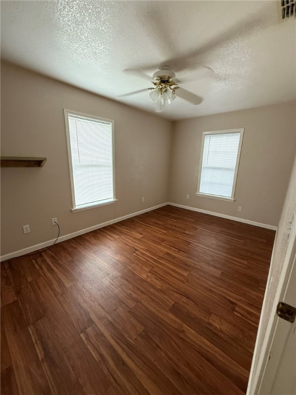 308 East 2nd Street Bishop, TX 78343 - Photo 6 of 12 an empty room with wooden floor chandelier fan and windows